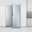 The front view of the refrigerator is shown in a kitchen. A blue square on the edge of the refrigerator and arrows highlight how it fits seamlessly into a standard kitchen.